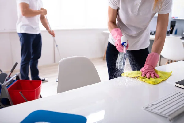 two people cleaning office with spray bottle and mop